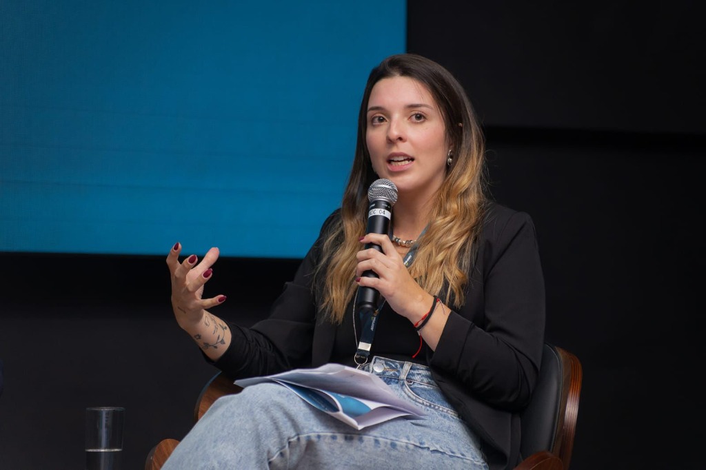 Sarah Antunes palestrando com microfone em evento de sustentabilidade